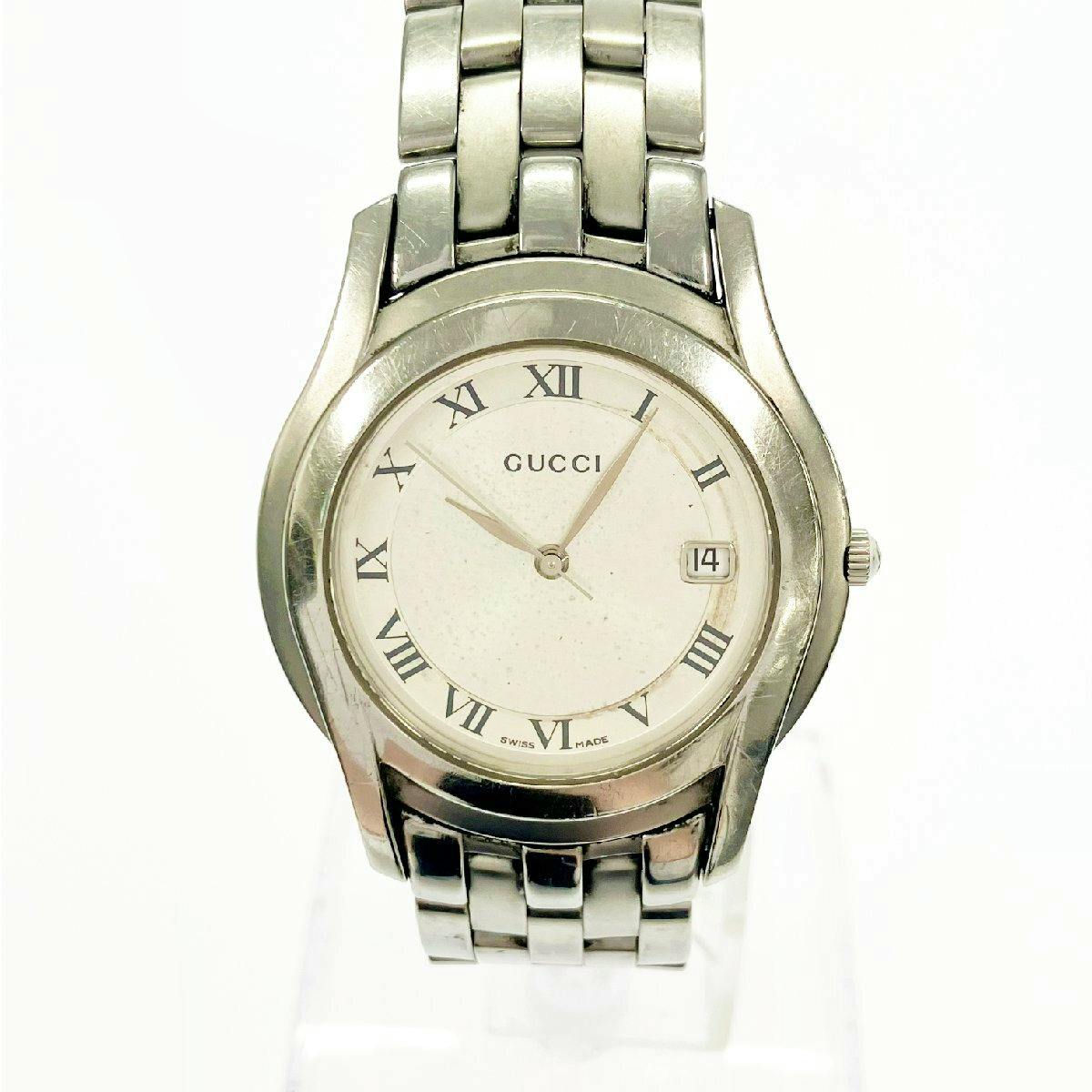 Front view of the GUCCI 5500M men's stainless steel wristwatch with silver dial, Roman numeral hour markers, and a date window at 3 o'clock.