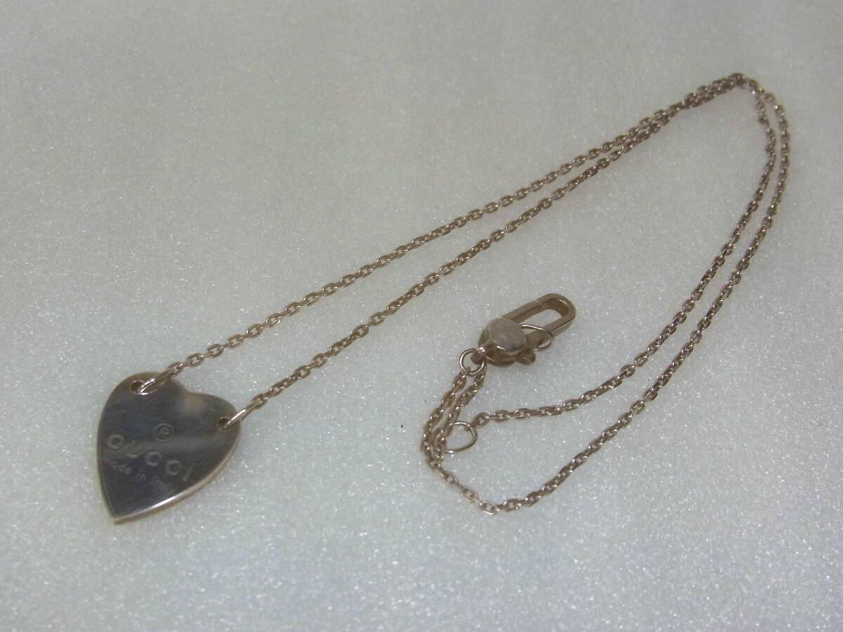 A GUCCI 925 silver heart pendant necklace with chain and clasp displayed on a white textured background.