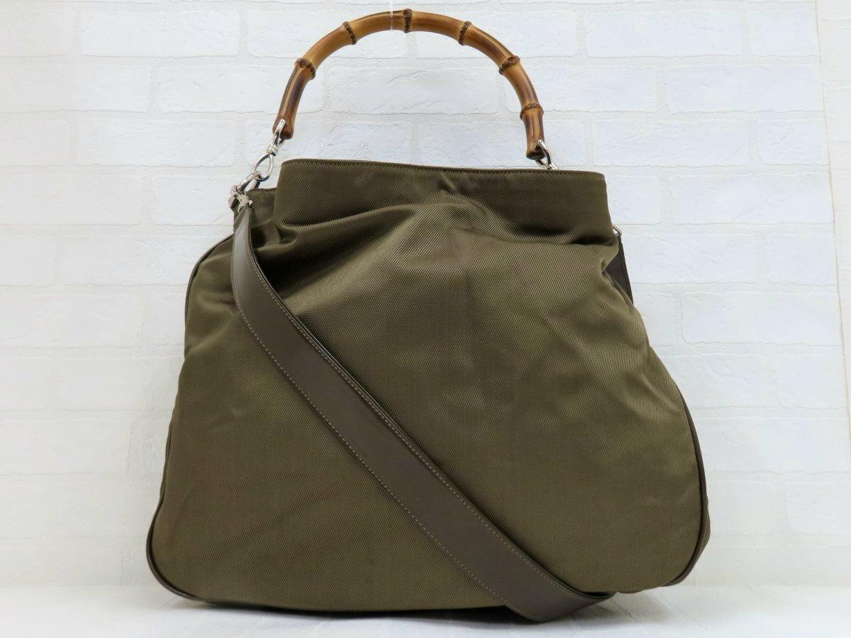 Front view of a brown Gucci 2-way nylon and calf leather bag with a bamboo top handle, leather shoulder strap, and silver hardware.