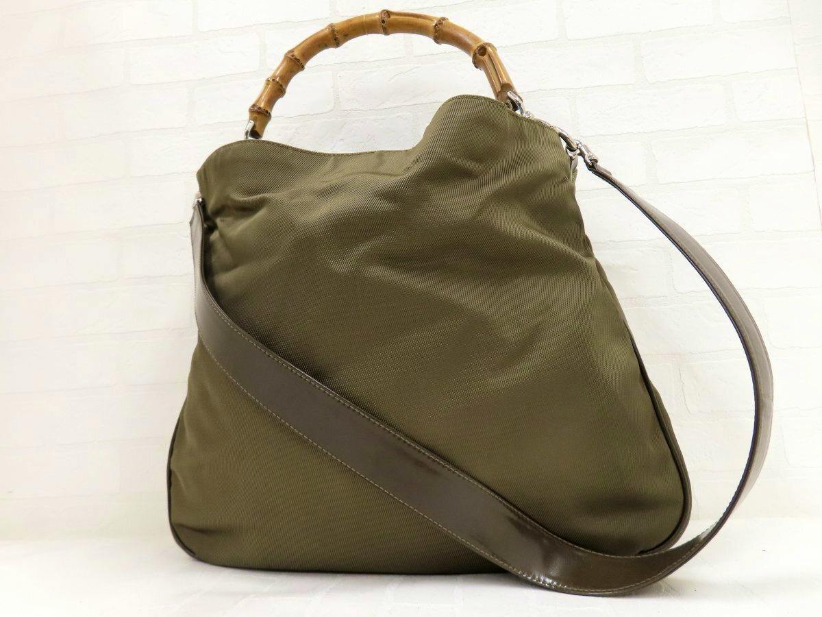 Olive-green nylon Gucci 2-way handbag shown front-on with a bamboo top handle and a brown leather shoulder strap.