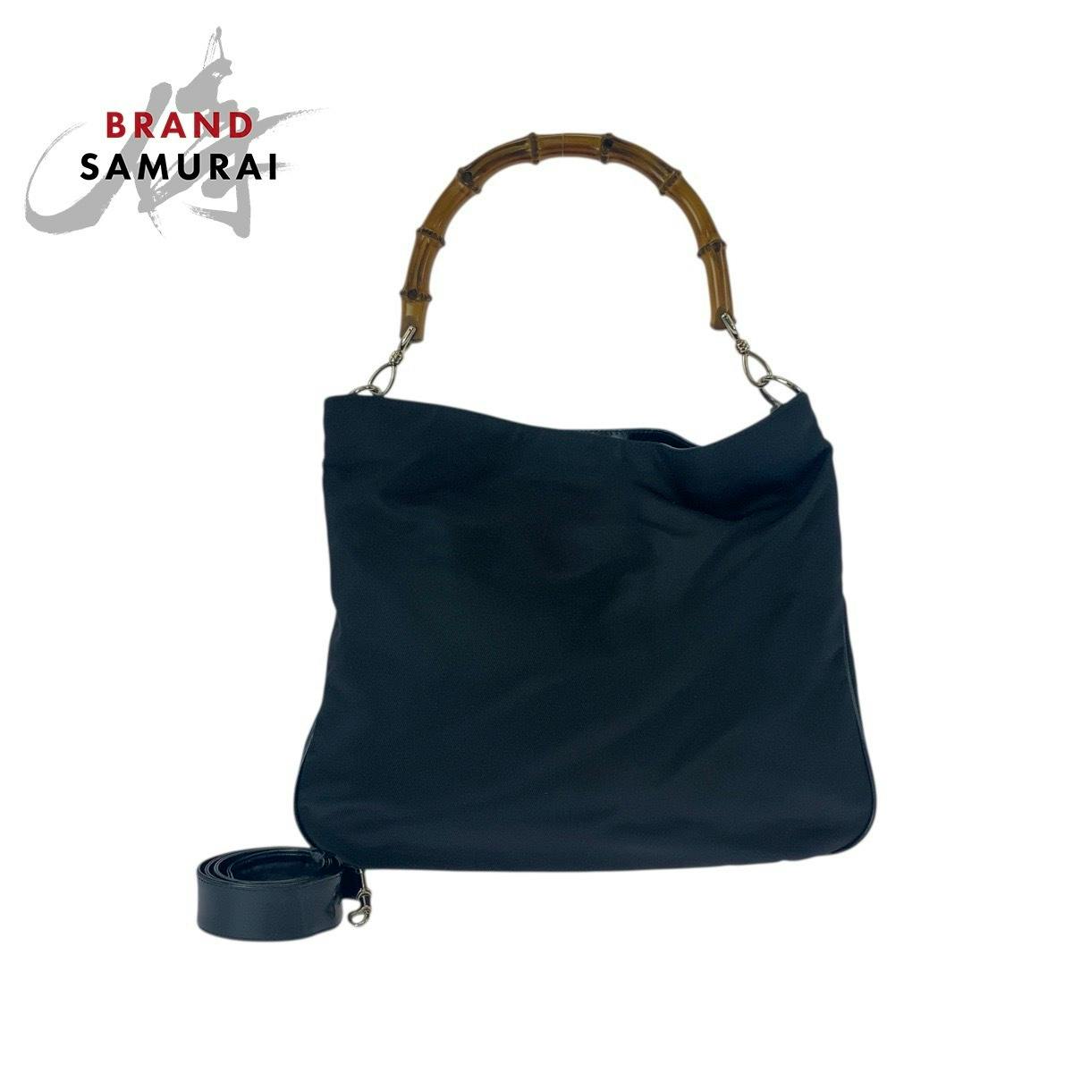 Black Gucci canvas shoulder bag with bamboo handle and detachable strap shown on a white background.