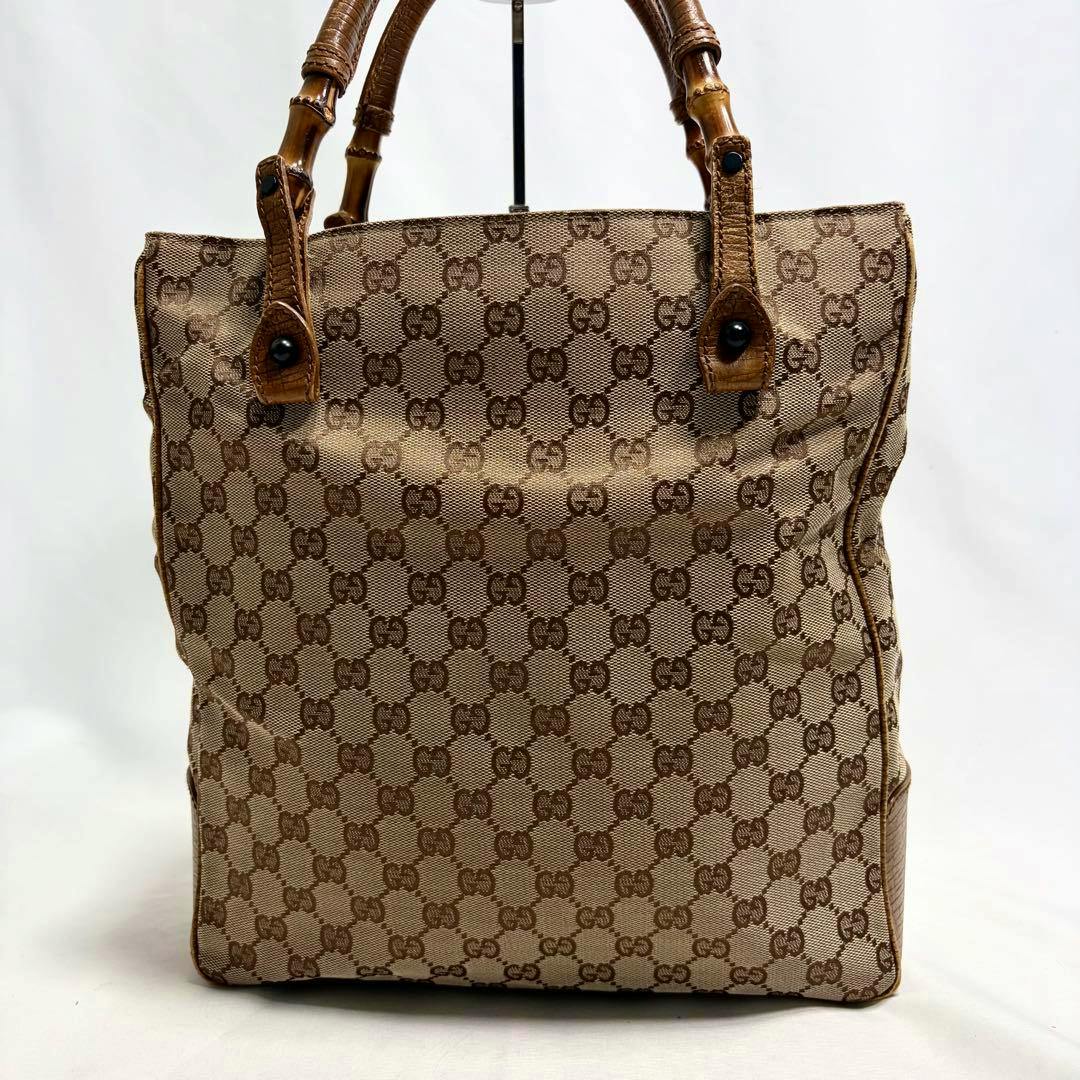 Front view of a Gucci canvas tote bag showing the GG monogram pattern and bamboo-style handles.