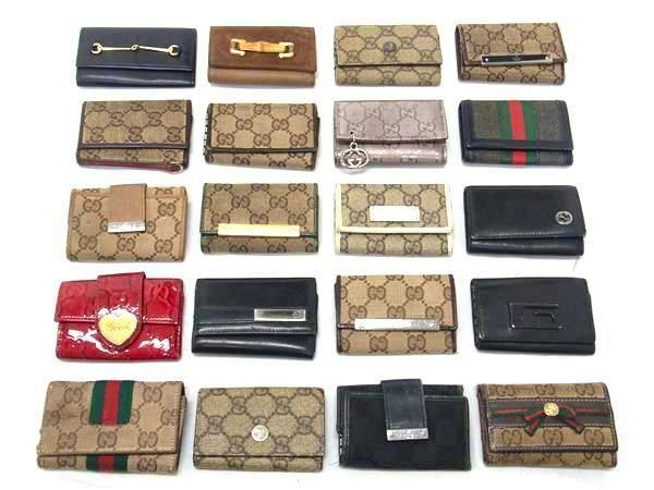 Twenty Gucci key cases in assorted GG canvas and leather laid out in rows on a white background.