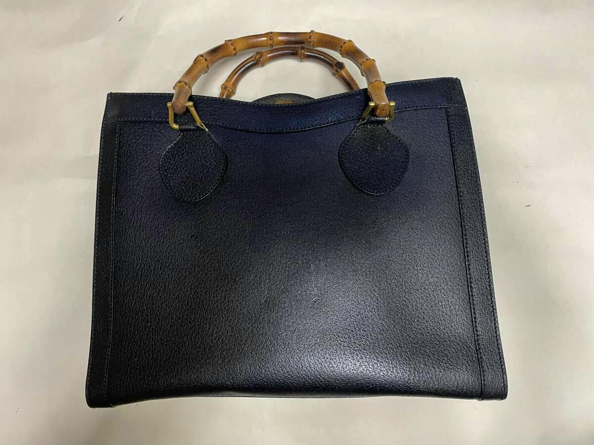 A black GUCCI bamboo-handle leather tote bag shown flat on a light background.