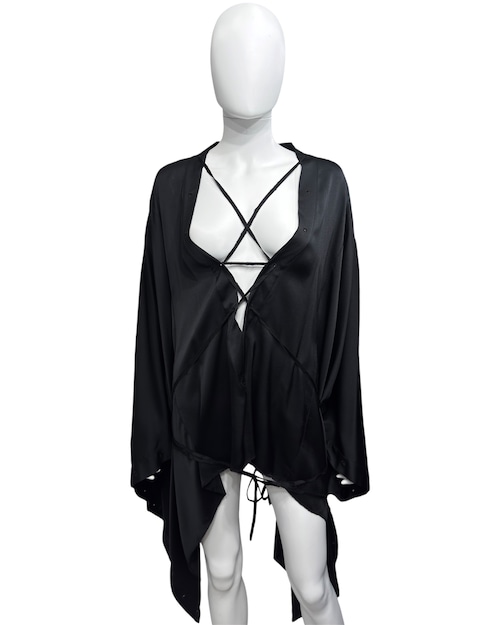 Mannequin wearing a black silk poncho with draped asymmetric hem and strappy front detail.