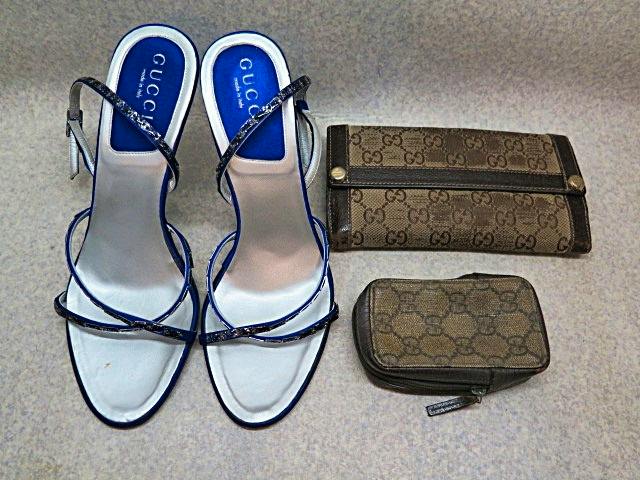 Three Gucci items laid on a surface: a pair of white-and-blue sandals and two brown GG canvas wallets/coin pouch.