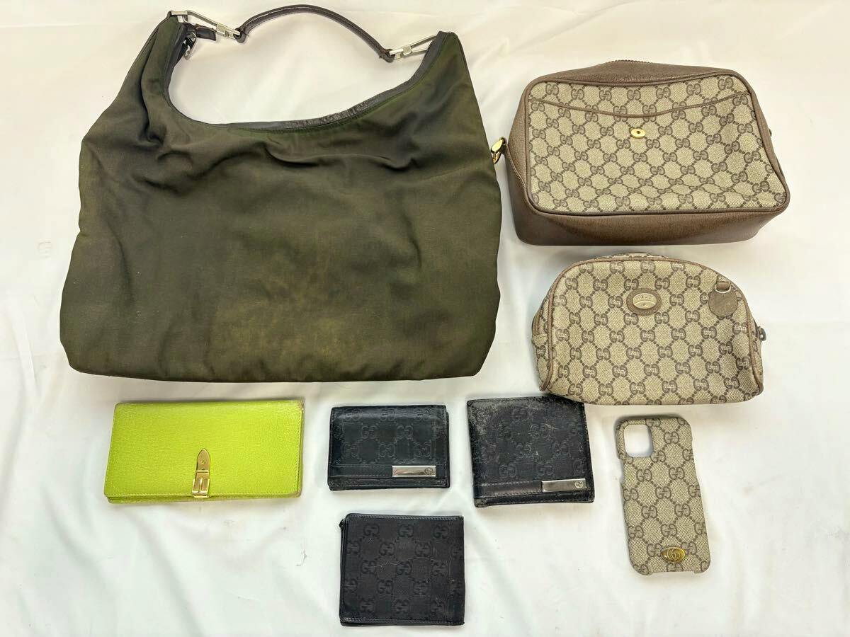 Laid-out Gucci set on white background showing a large green shoulder bag, two beige GG monogram pouches, several wallets, and a beige GG phone case.