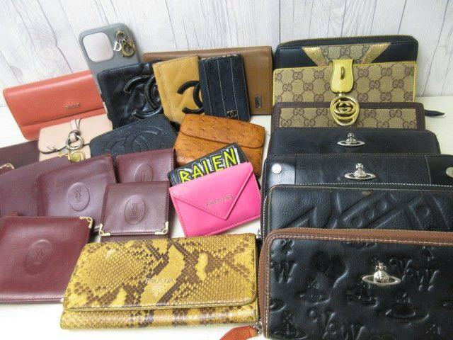 A group of assorted wallets, key cases, and small leather cases arranged on a surface, showing various colors, textures, and logos.