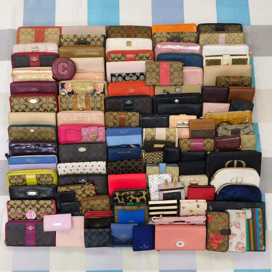 A large assortment of wallets and small leather accessories arranged in rows on a checkered background.