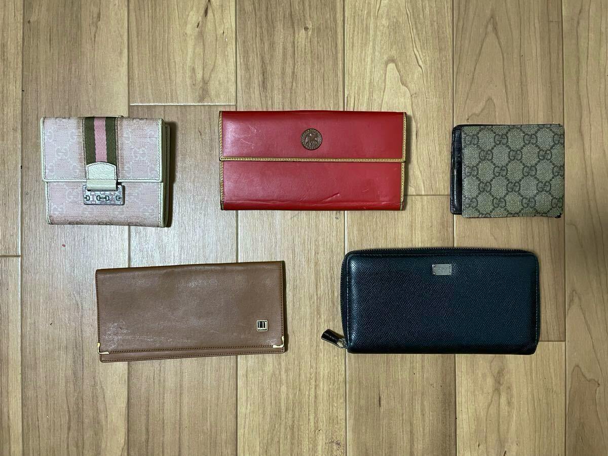 Five wallets arranged on a wooden floor, displayed together as a set.