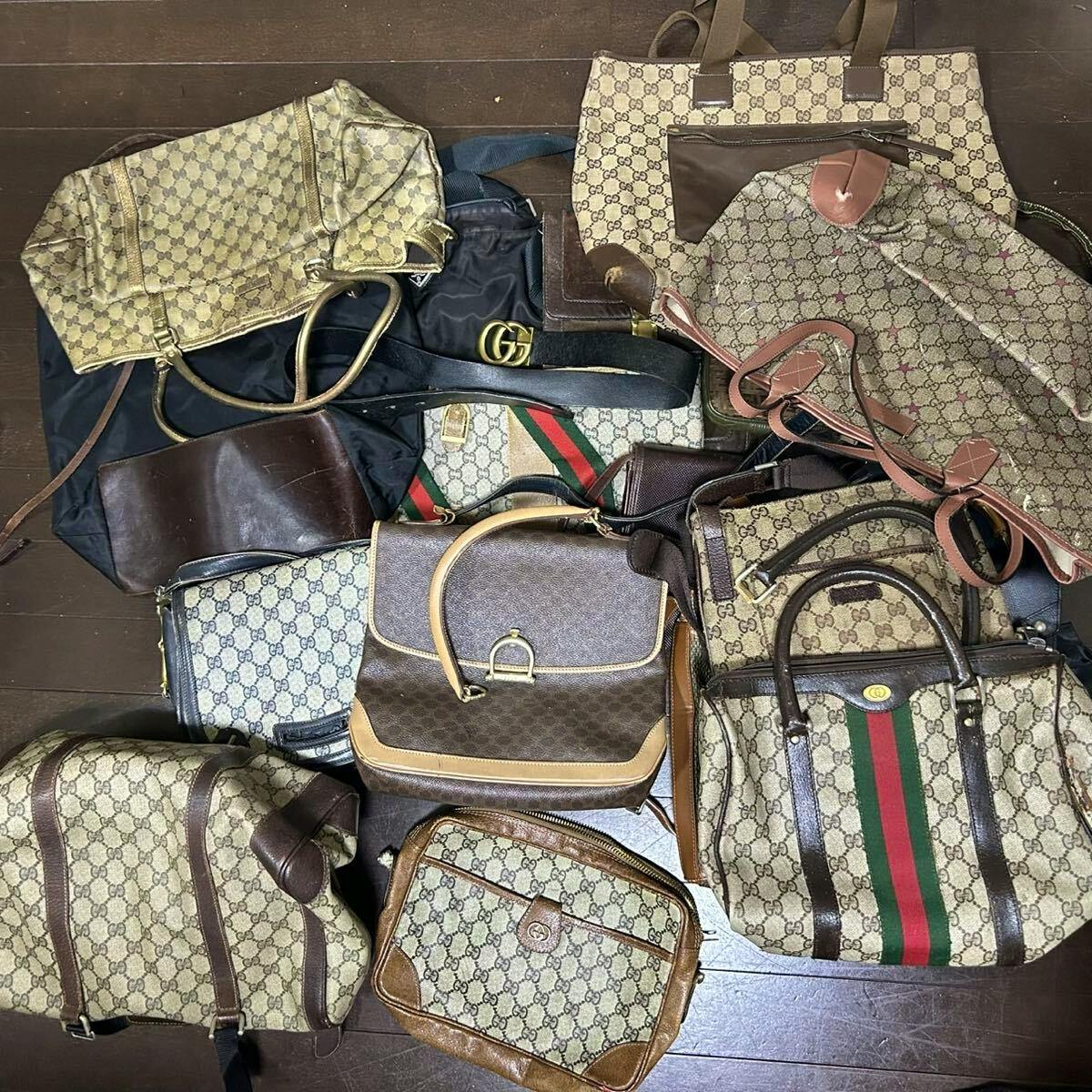 Top-down photo showing many canvas brand bags, including multiple Gucci monogram bags, laid out on a floor.