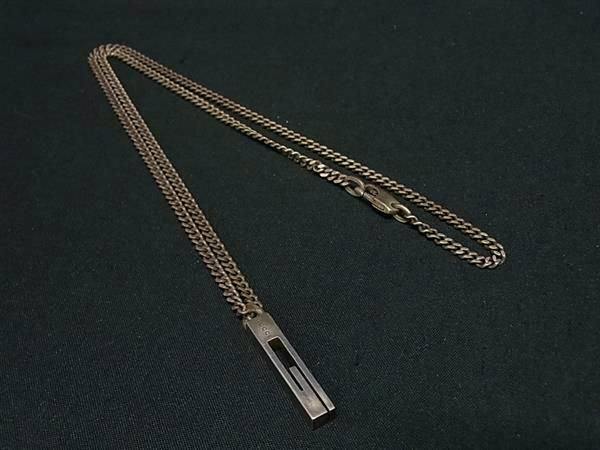 GUCCI silver-tone chain necklace with a rectangular pendant laid flat on black fabric.