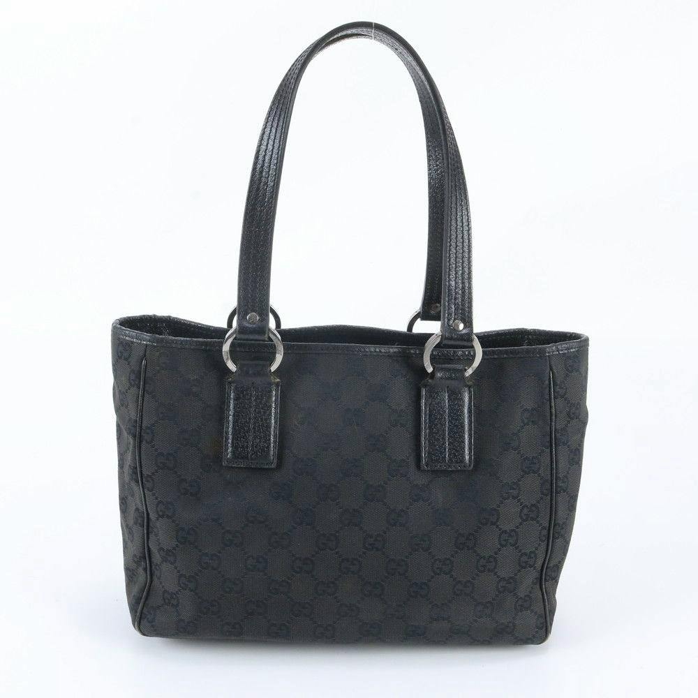Front view of a black Gucci GG canvas tote bag with leather shoulder handles on a white background.
