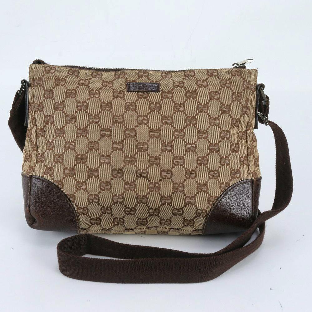 Front view of a Gucci GG canvas shoulder crossbody bag with leather corner reinforcements and a brown fabric strap.