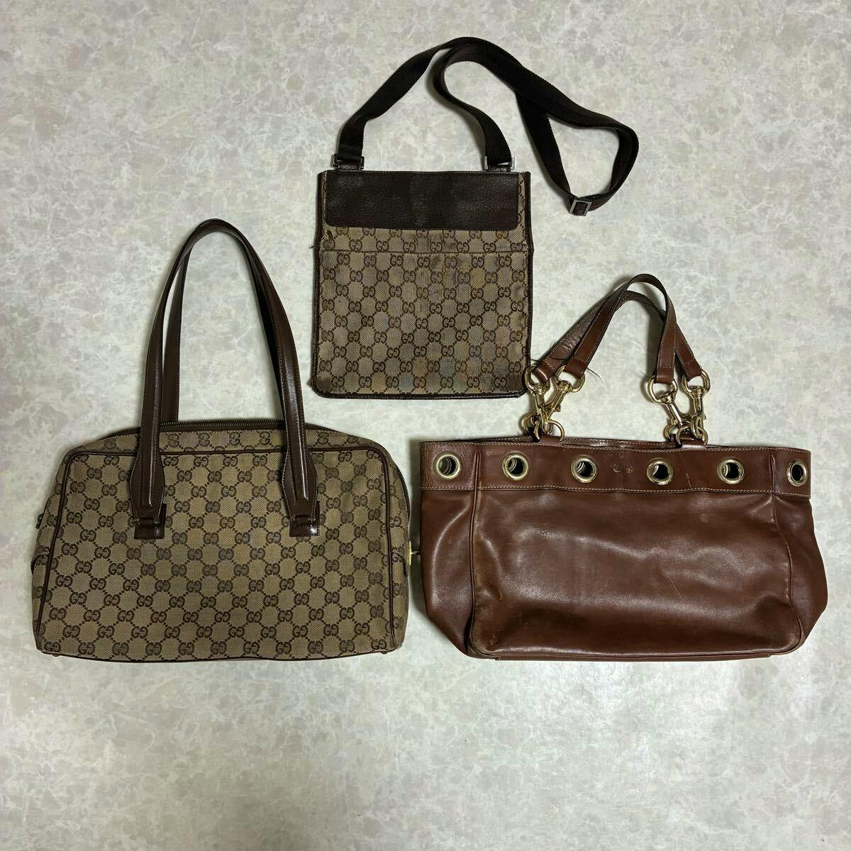 Three GUCCI bags, two GG canvas bags and one brown leather tote, arranged flat on a light surface.