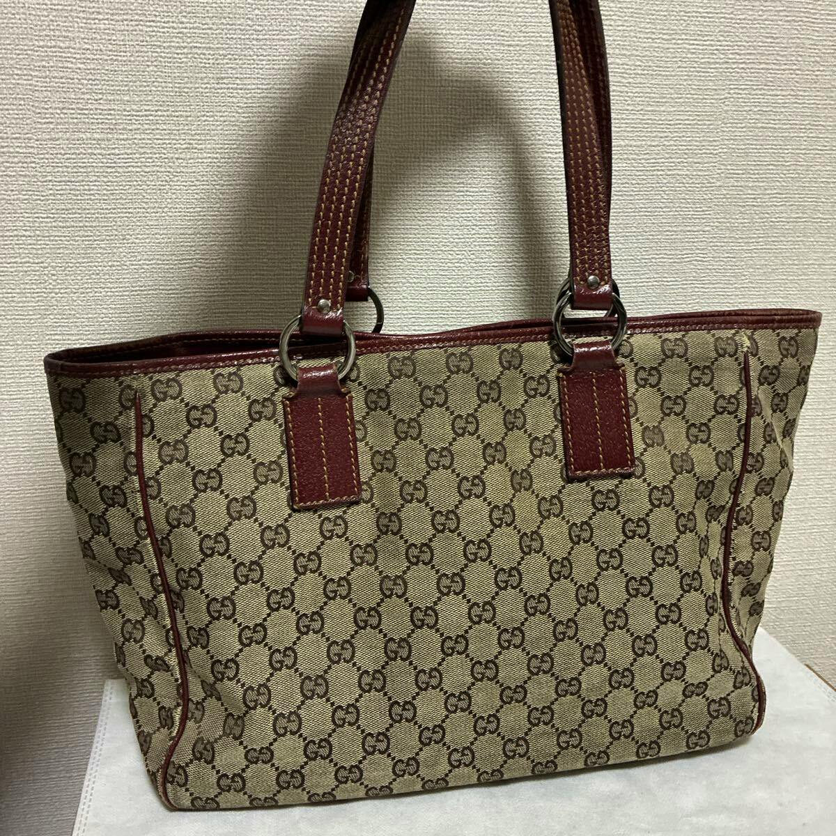 Front view of a GUCCI GG canvas tote bag in beige-brown with red-brown leather trim and two handles.