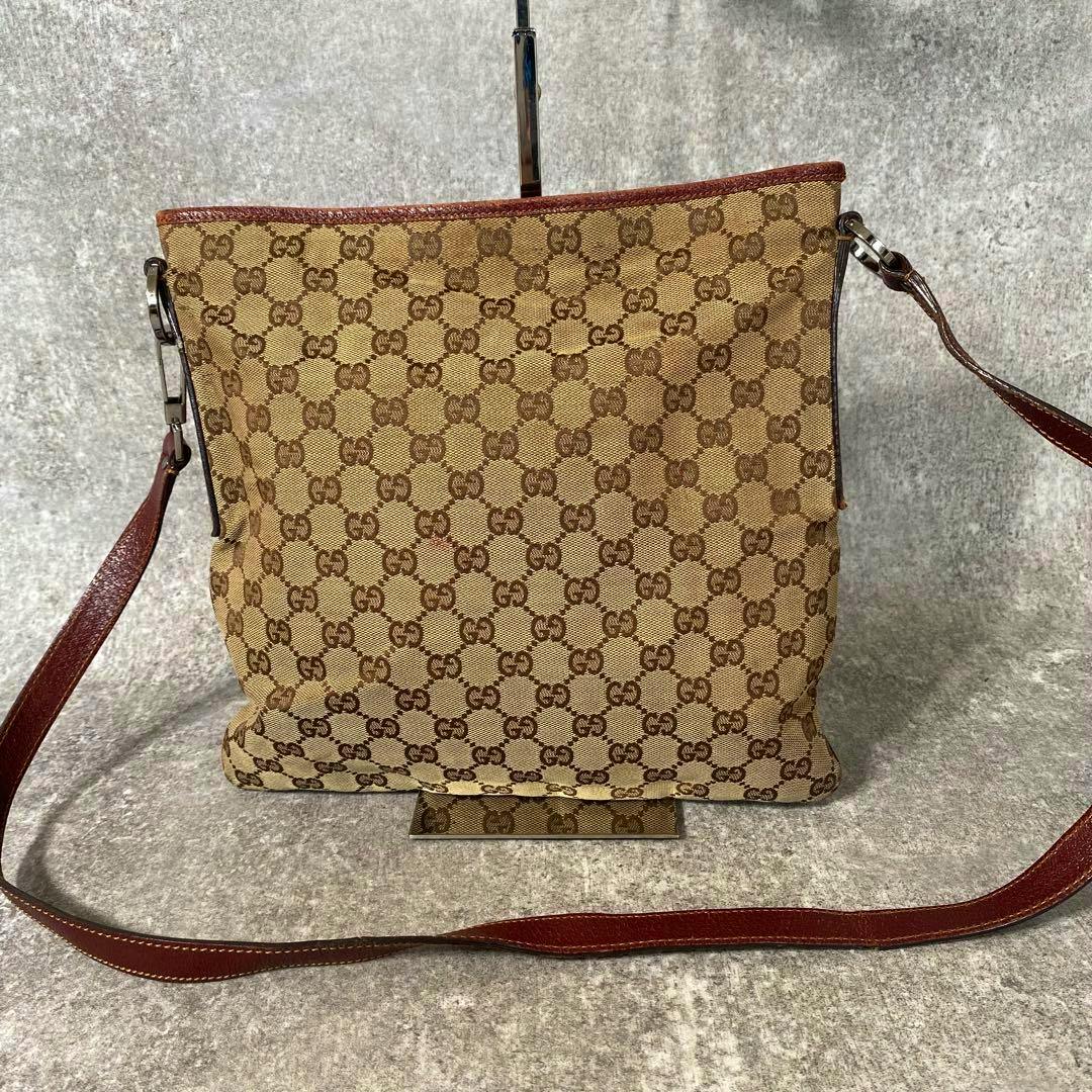 Front view of a brown GUCCI GG canvas shoulder sacoche showing the monogram pattern and a brown leather strap.