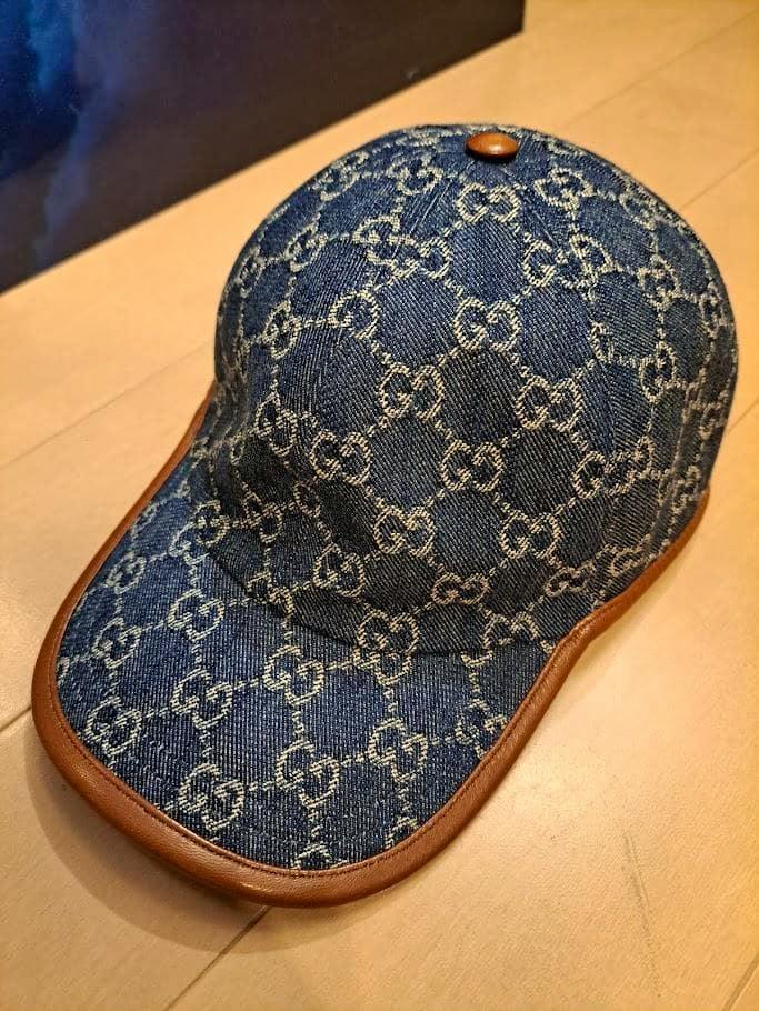 Blue GUCCI GG canvas denim baseball cap shown on a wooden surface.
