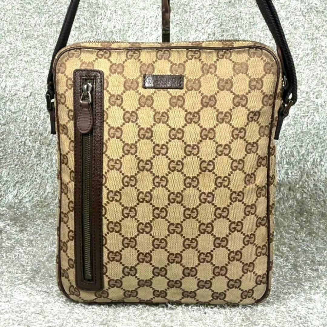 Front view of a Gucci brown GG canvas shoulder bag with leather trim and a vertical zip pocket.