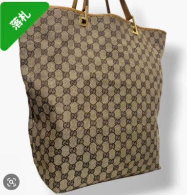 Front view of a Gucci GG canvas tote bag with leather handles and hardware.