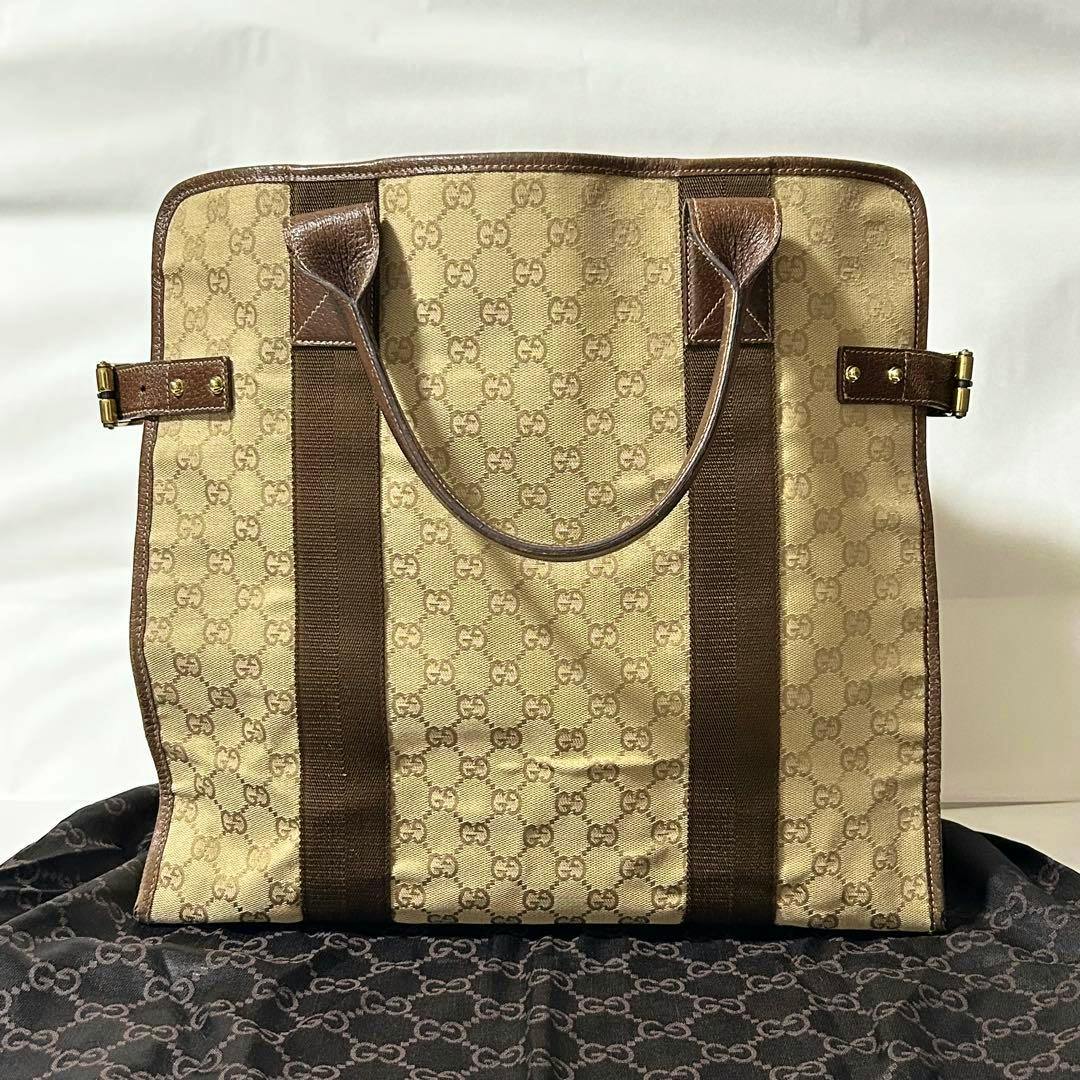 Beige GUCCI GG canvas tote handbag with brown leather trim and dual handles shown front-facing.