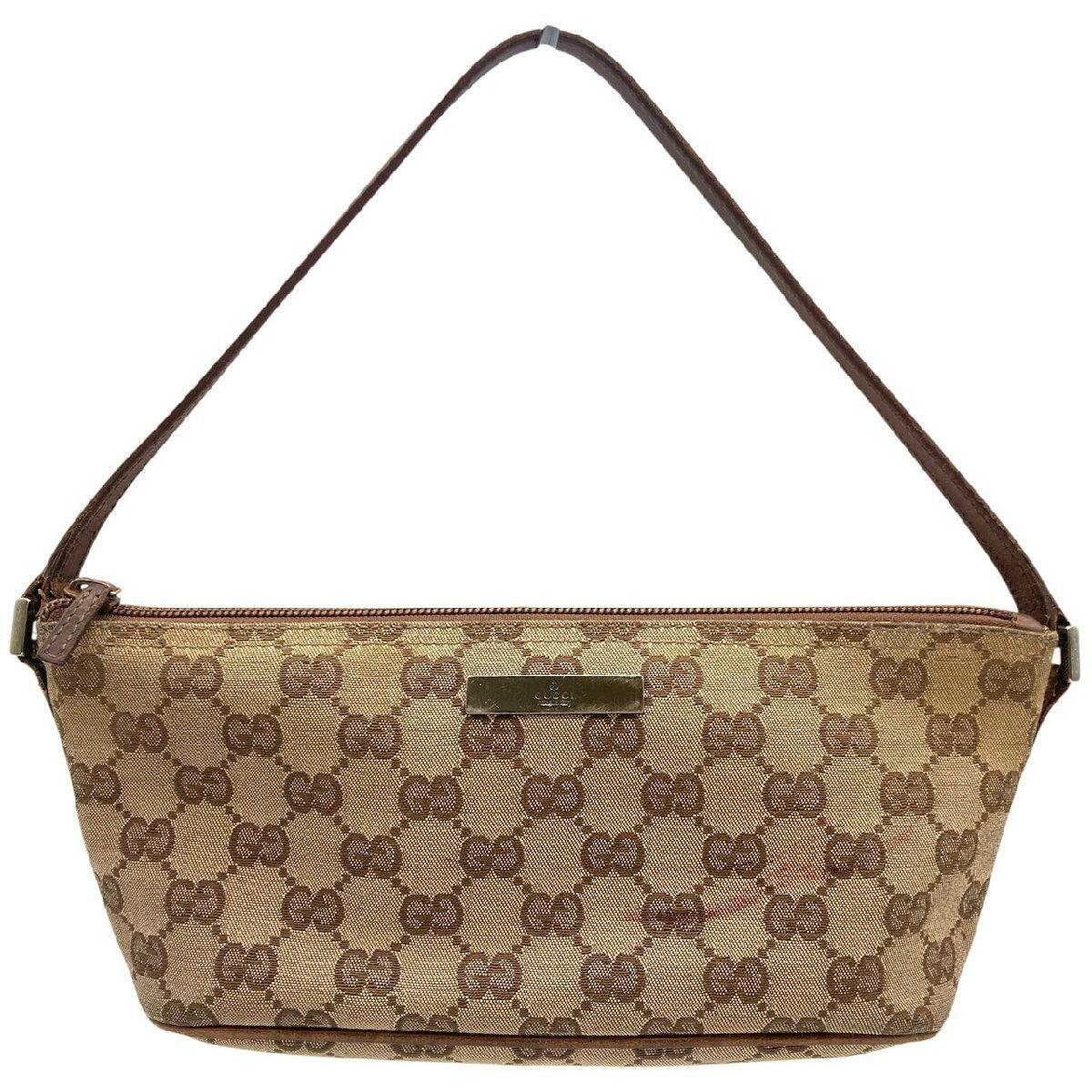 Front view of a beige and brown Gucci GG canvas accessory pouch with a brown leather strap and a metal logo plate.