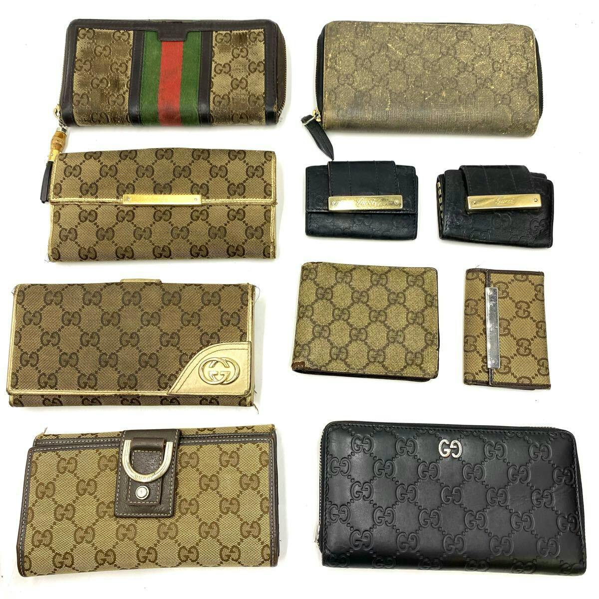 Ten Gucci GG canvas and leather wallets, card cases and key cases arranged on a white background showing monogram pattern and metal hardware.