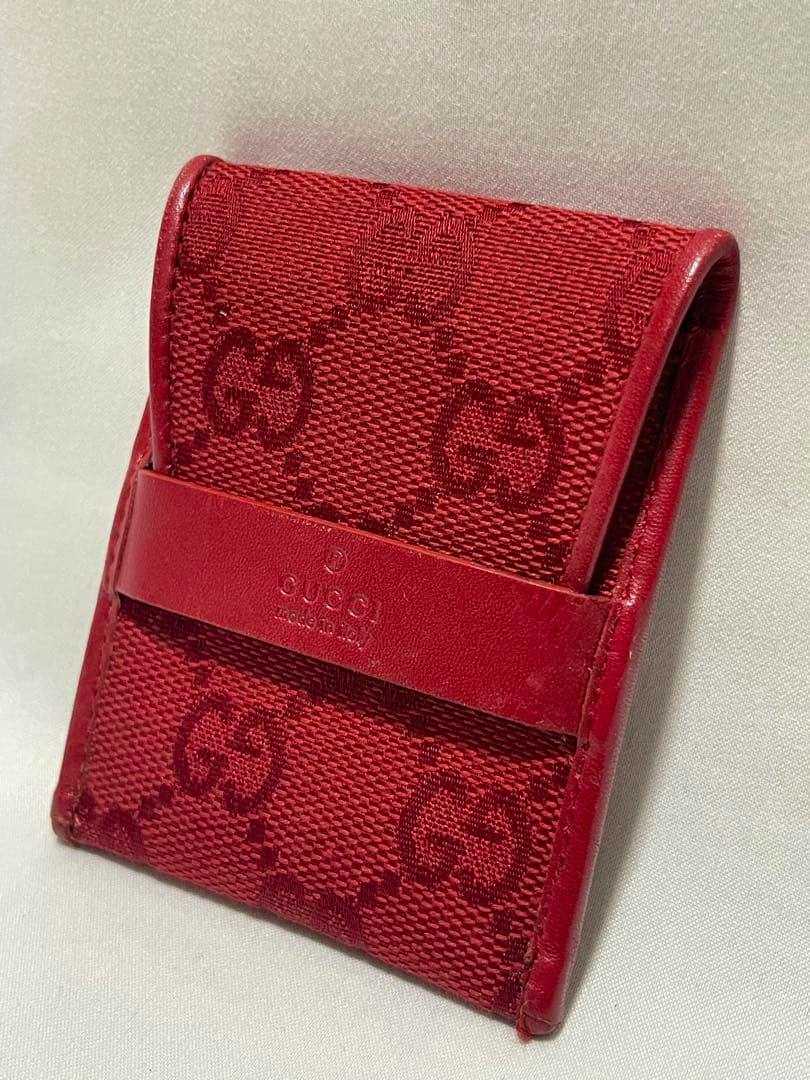Red GUCCI GG canvas coin case with leather strap shown in an angled front view.