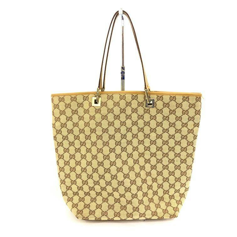 Front view of a GUCCI GG canvas tote bag with beige monogram pattern, leather trim, and double shoulder straps.