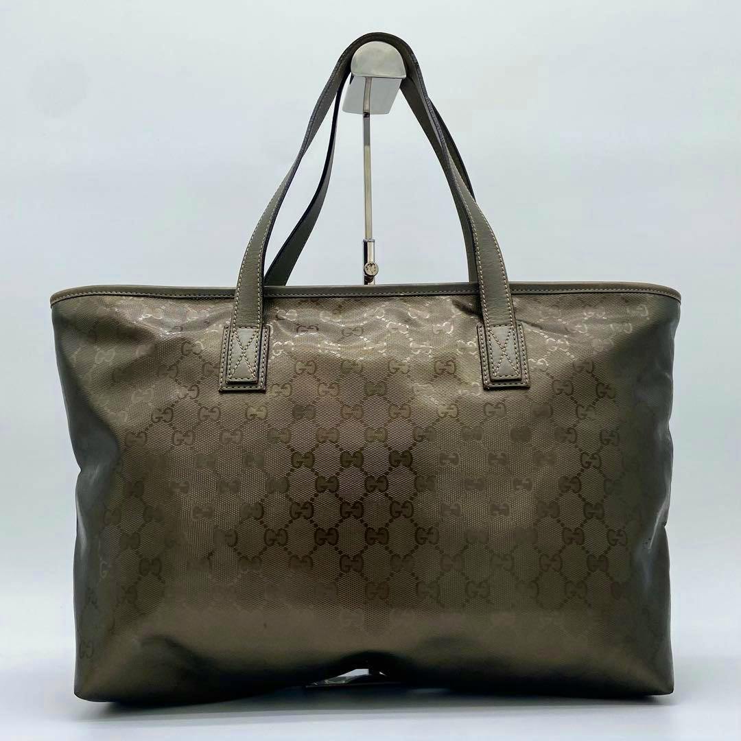 Front view of the Gucci PVC shoulder bag with embossed GG monogram pattern and two top handles displayed on a stand.