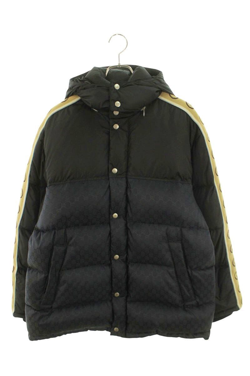 Front view of the black Gucci nylon down men's jacket (size 48) with hood, snap-button closure, and beige shoulder stripes showing GG motif.
