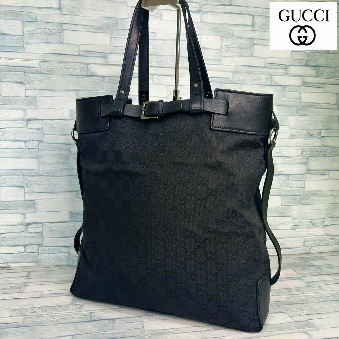 Black Gucci GG-patterned tote handbag displayed upright against a light tiled background.