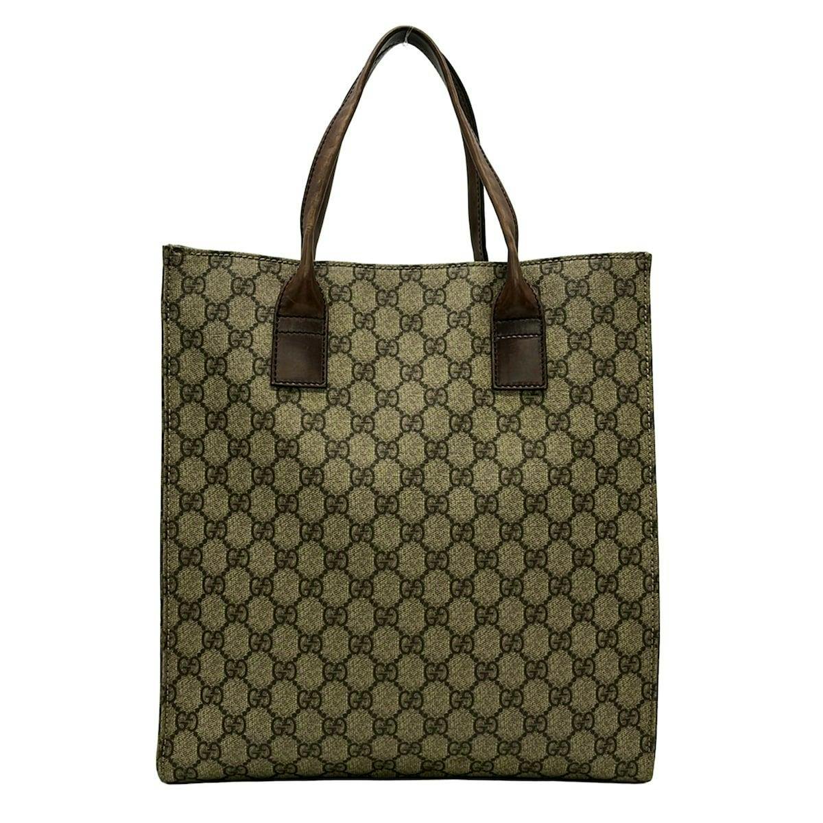 Front view of the GUCCI tote bag in beige GG Supreme canvas with dark brown leather handles.