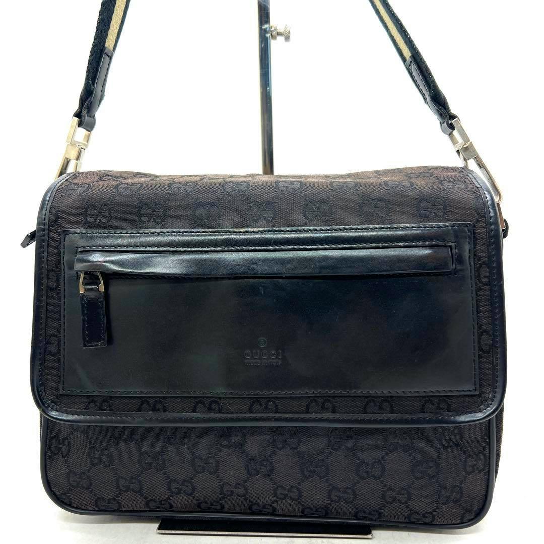 Front view of a black Gucci GG canvas sacoche shoulder bag with a leather front pocket and strap.