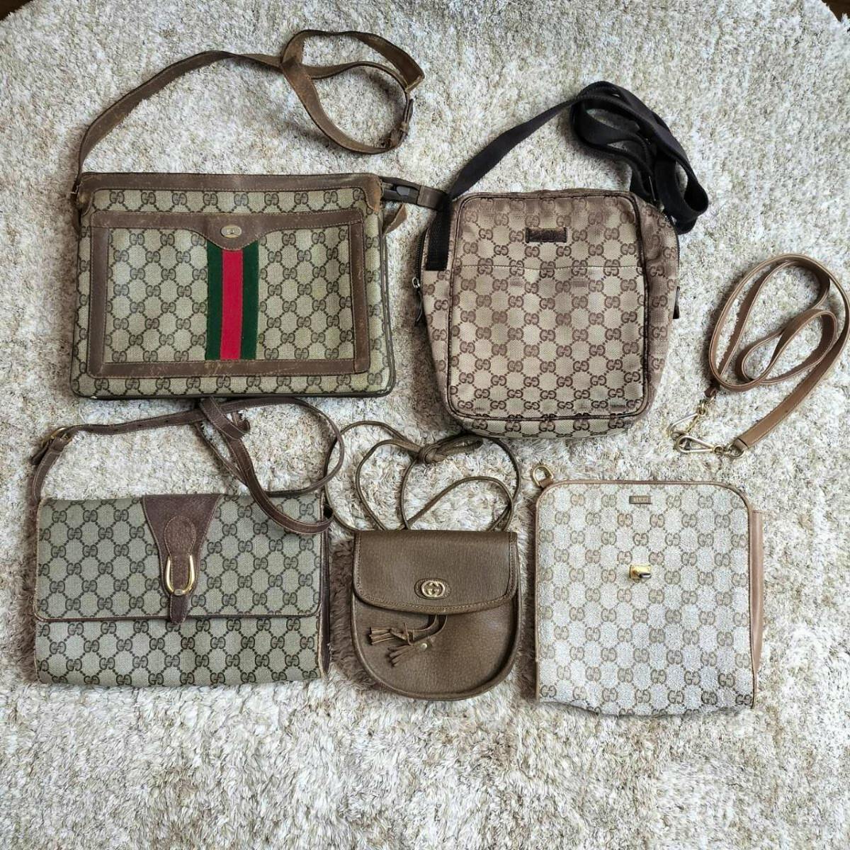 Five brown GG Supreme canvas Gucci shoulder bags and straps laid out on a light-colored rug.