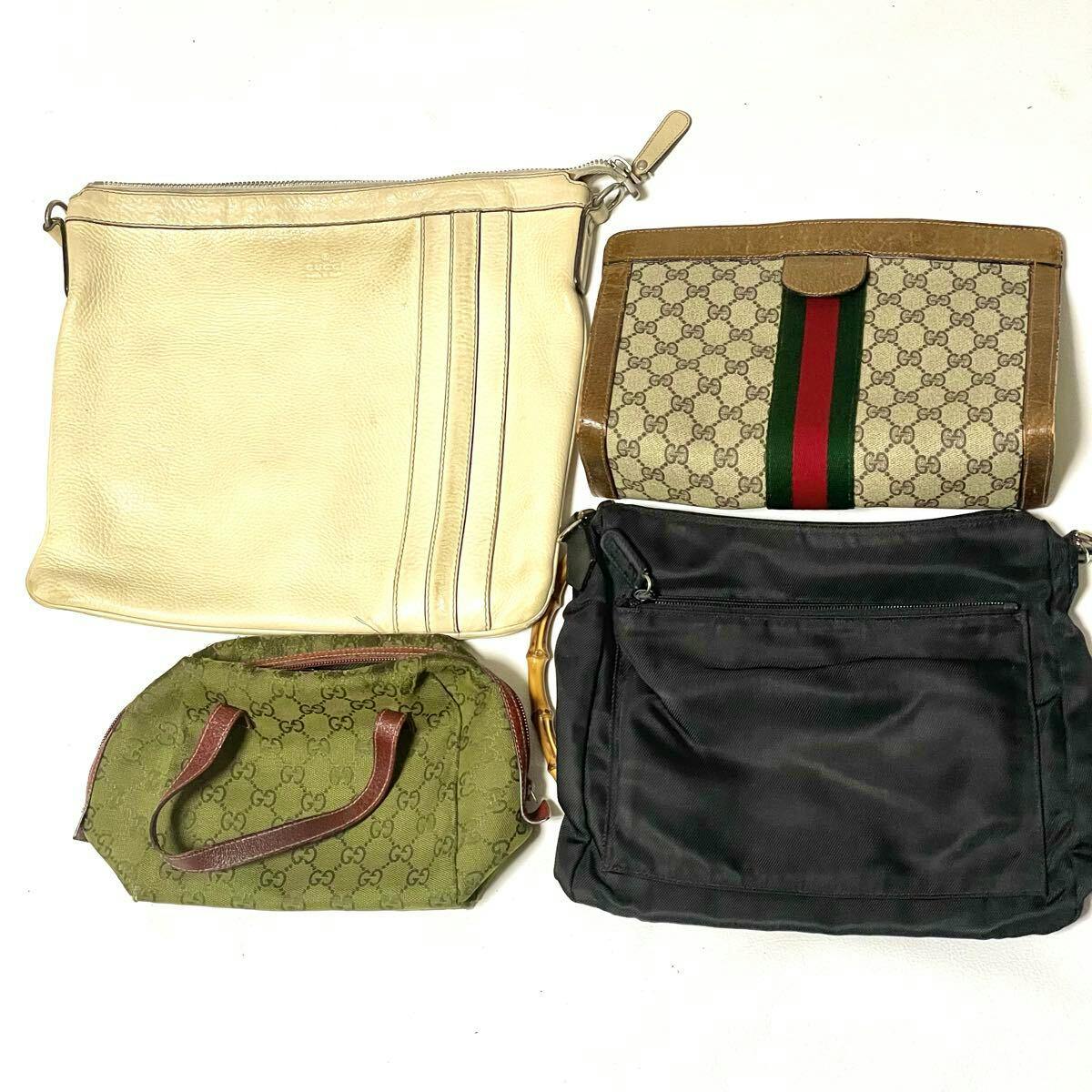 Four Gucci bags on a white background: a cream leather tote, a beige GG canvas clutch with green-red stripe, a small green GG monogram bag, and a black nylon shoulder bag.