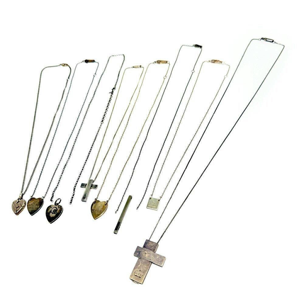 Eight GUCCI necklaces with various heart and cross pendants laid out on a white background.