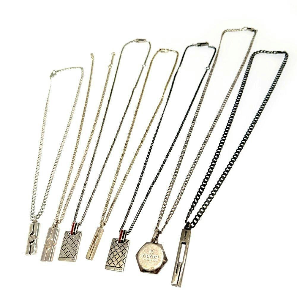 Seven GUCCI necklaces with different pendants and chains laid flat on a white background.