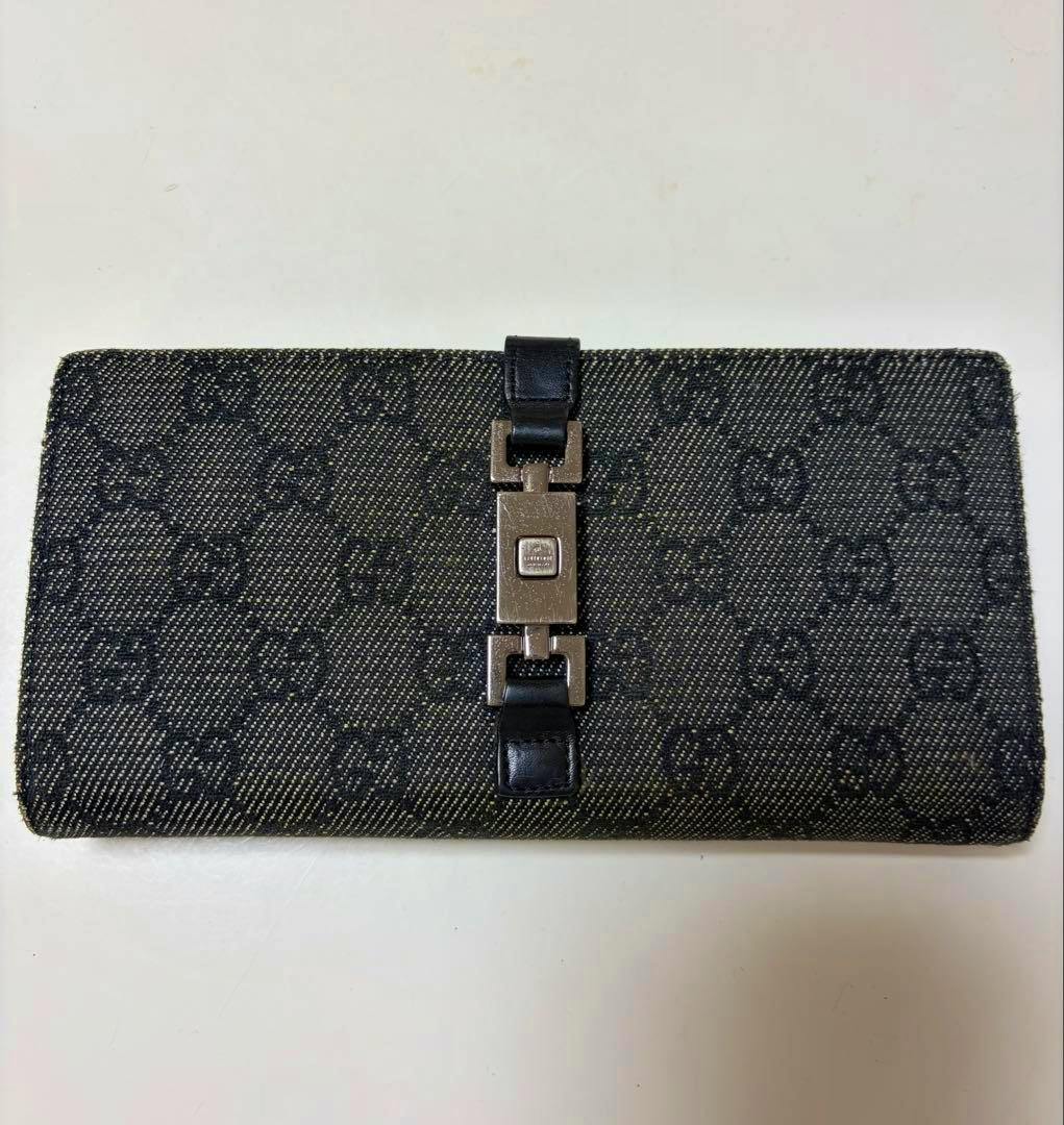 Front view of a GUCCI Jackie long wallet in GG canvas with a leather strap and metal clasp.