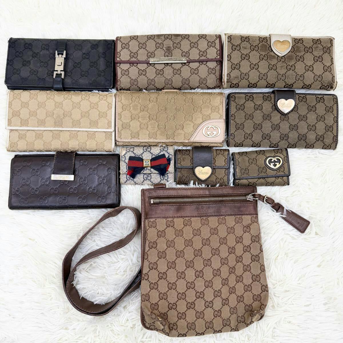 Eleven Gucci wallets and a GG-pattern shoulder bag arranged on a white surface, showing various GG canvas designs and heart embellishments.