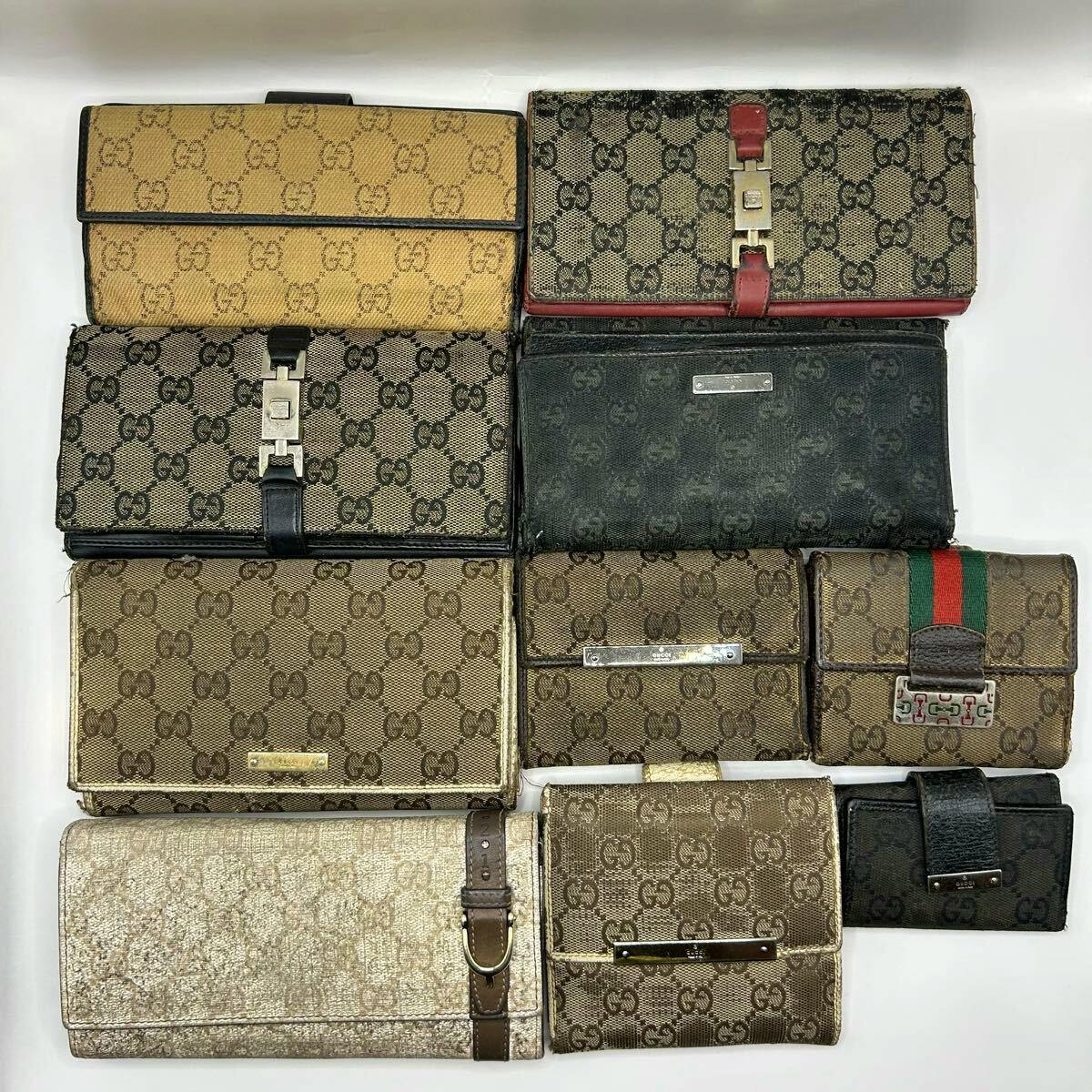 Ten Gucci monogram wallets and small leather goods arranged on a white background showing various styles and visible wear.