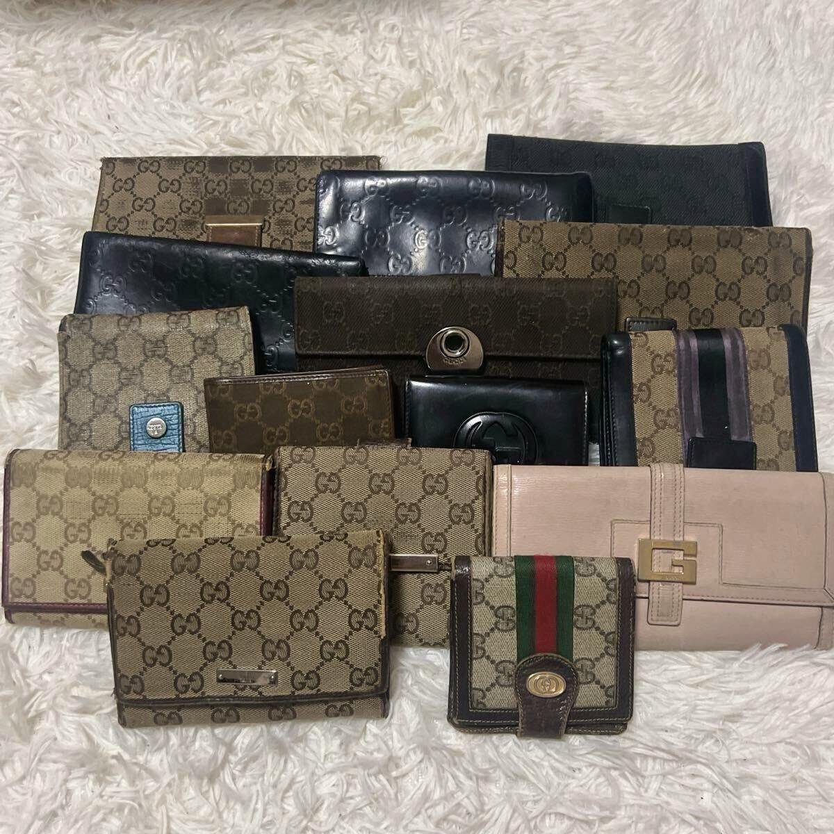 A group of Gucci wallets in GG canvas and leather arranged on a white fuzzy rug.