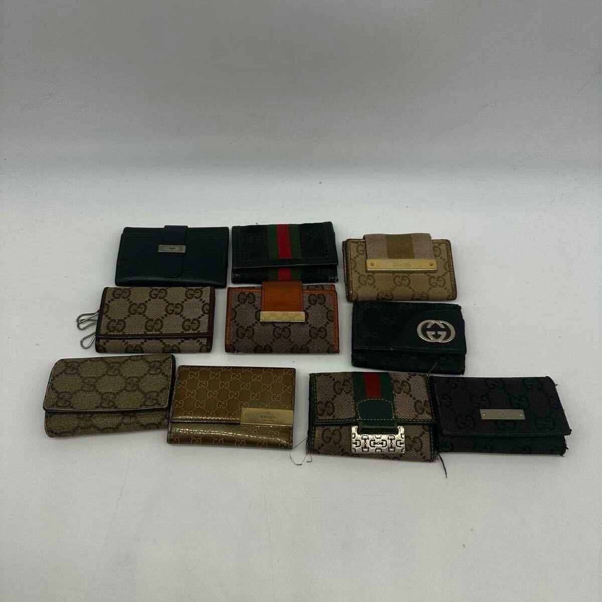 Ten Gucci key cases in various GG canvas and leather styles arranged on a white background.