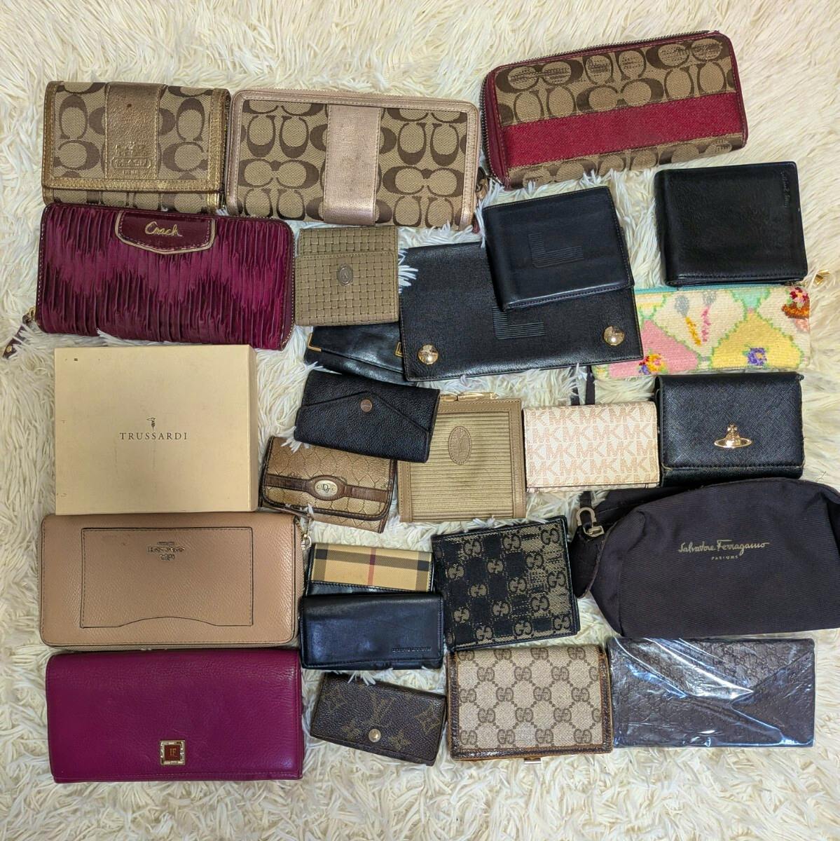 Top-down photo of multiple wallets and small leather goods laid out on a rug showing assorted designer patterns and leather finishes.