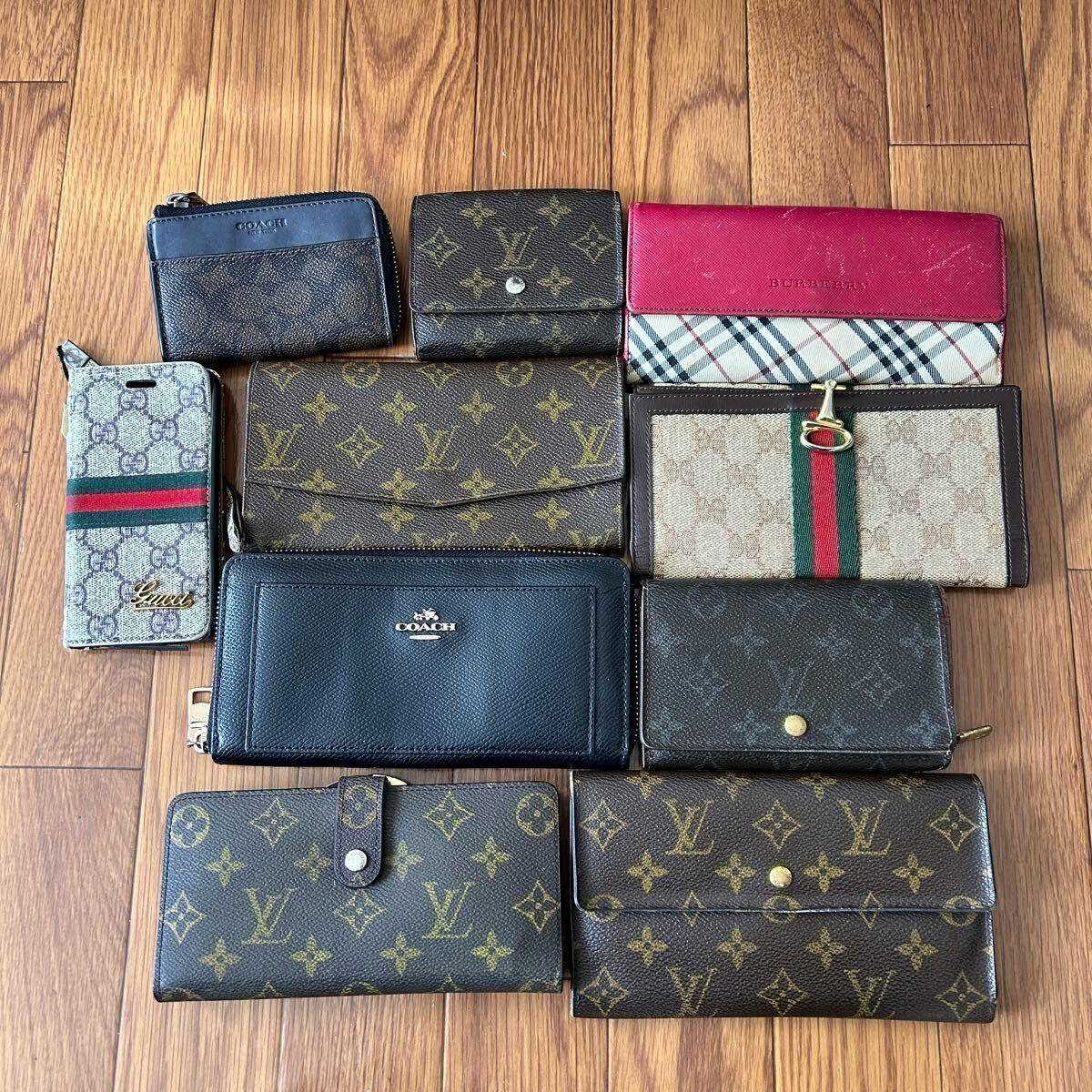 Ten assorted wallets, key cases, and small leather goods arranged on a wooden floor showing various monogram and canvas designs.