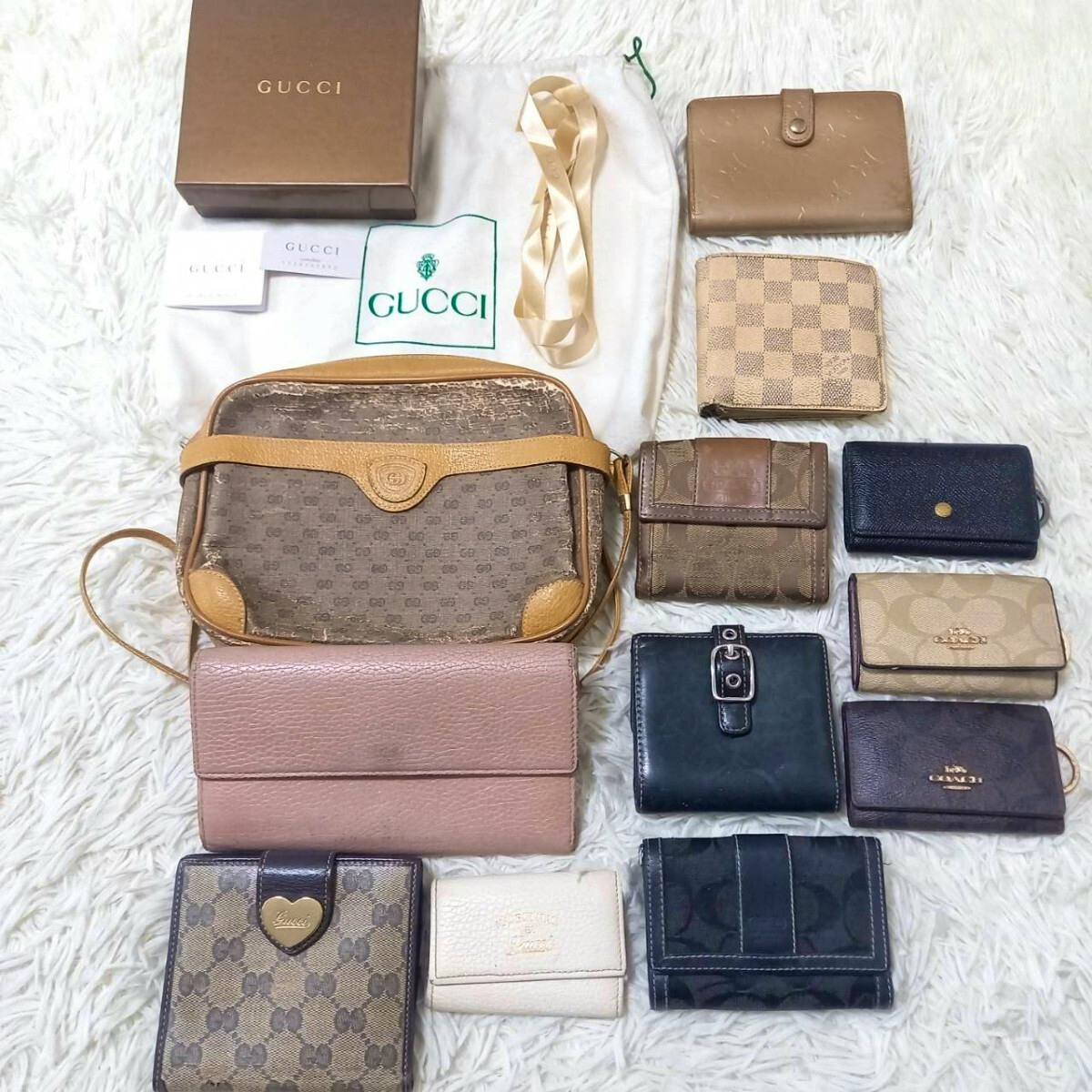 Top-down photo of multiple bags and wallets including a GUCCI bag and other branded wallets arranged on a white surface.