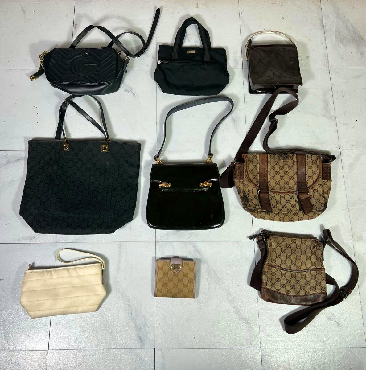 Nine GUCCI bags and accessories arranged on a tiled floor, including GG canvas shoulder bags, a tote, wallets and pouches.