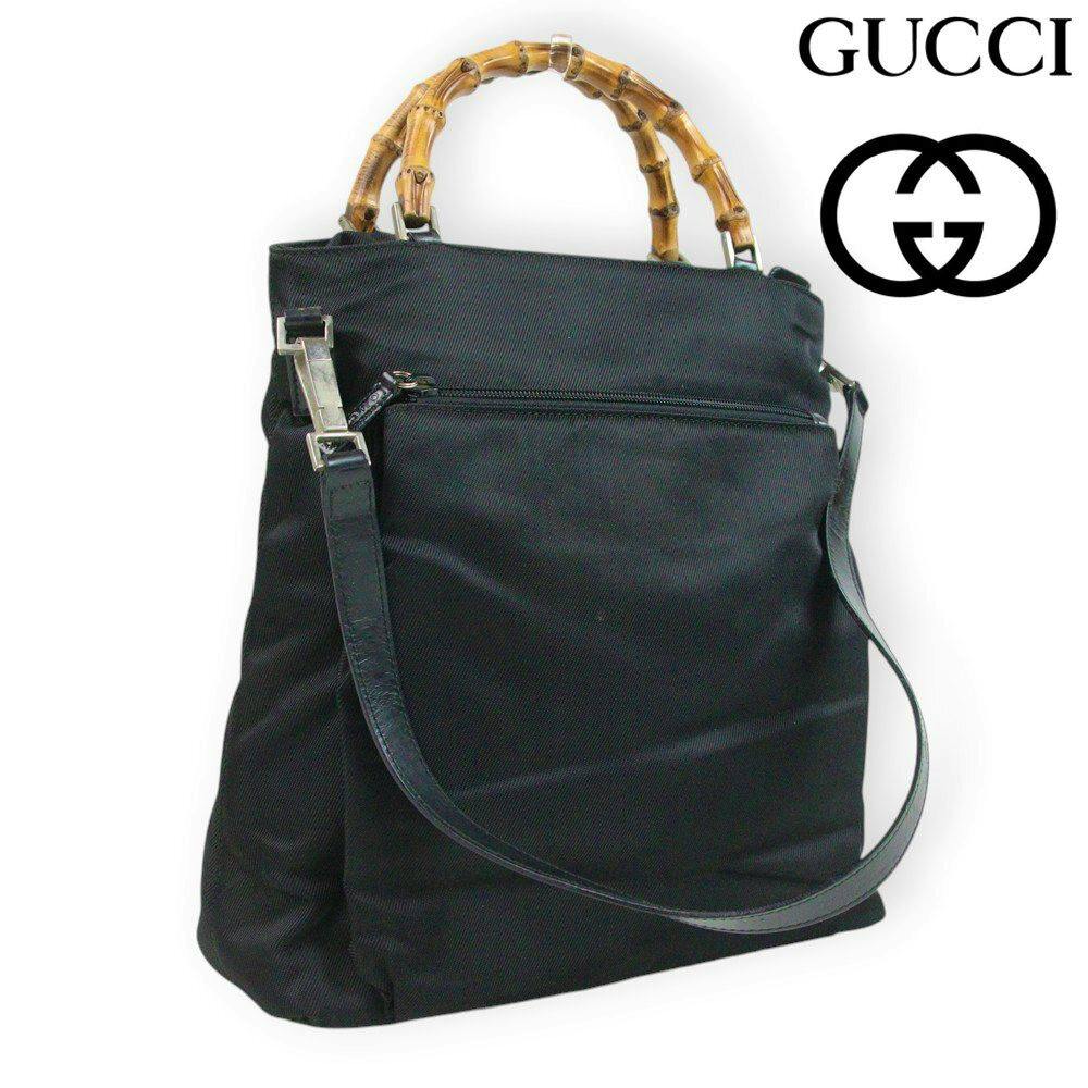 Black Gucci nylon 2-way handbag with bamboo top handles and a detachable shoulder strap shown on a white background.