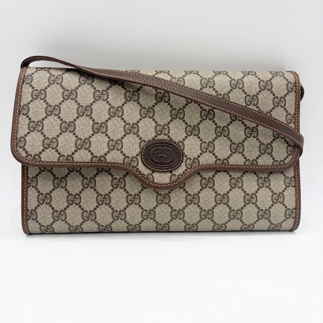 Front view of a Gucci GG Supreme flap shoulder bag with brown leather trim and shoulder strap.