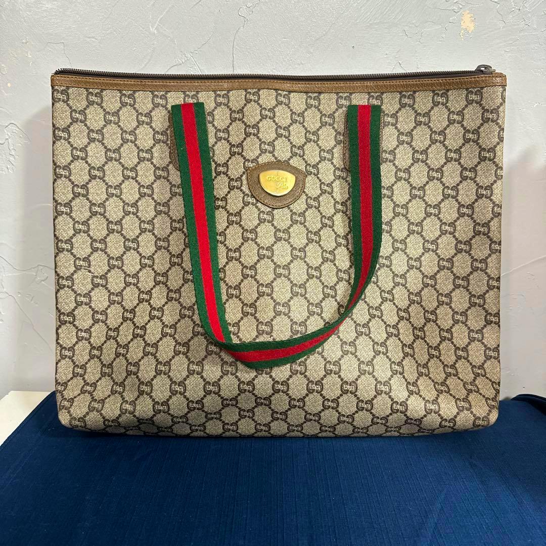 Front view of a GUCCI Plus beige GG monogram tote bag with green and red striped handles.